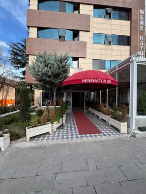 L’entrée d’un hôtel, surmontée d’un auvent rouge portant l’inscription « Nenehatun 59 ».
