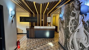 Una recepción con un letrero de 'Bienvenido', baldosas de suelo estampadas y una pared decorativa con un timón de barco.