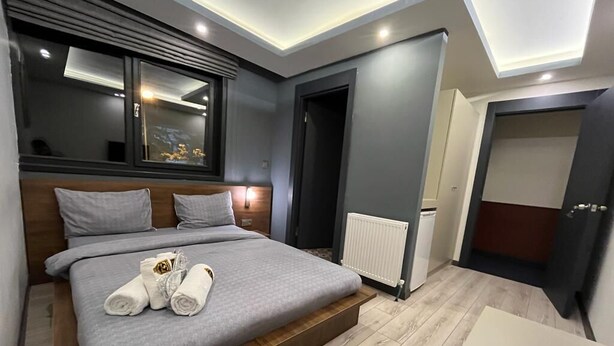 Un dormitorio moderno con cama, mesitas de noche, una ventana y una puerta.