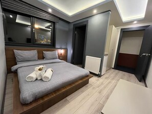 Une chambre à coucher moderne avec un lit, des tables de chevet, une fenêtre et une porte.