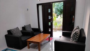 A living room with two black sofas, a wooden coffee table, and patterned throw pillows. - galtri homestay (Banyuwangi)