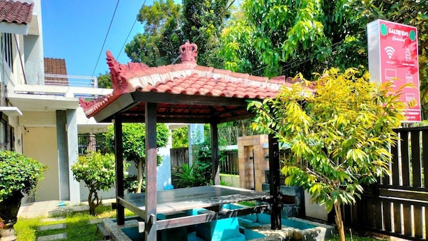 A traditional gazebo with a tiled roof, a small pool, and a stone pathway leading to it. - galtri homestay (Banyuwangi)