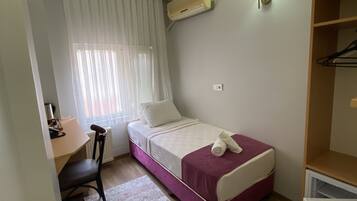 Una habitación pequeña con cama, escritorio, silla, radiador y armario.