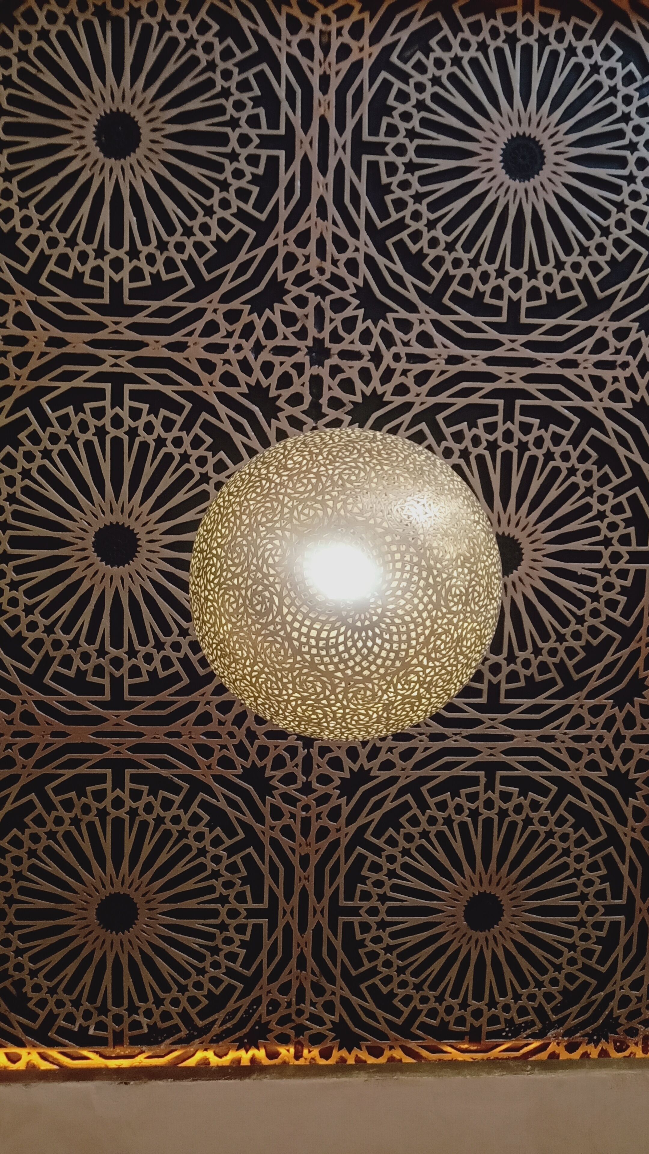 A wall with intricate geometric patterns and a central spherical light fixture.