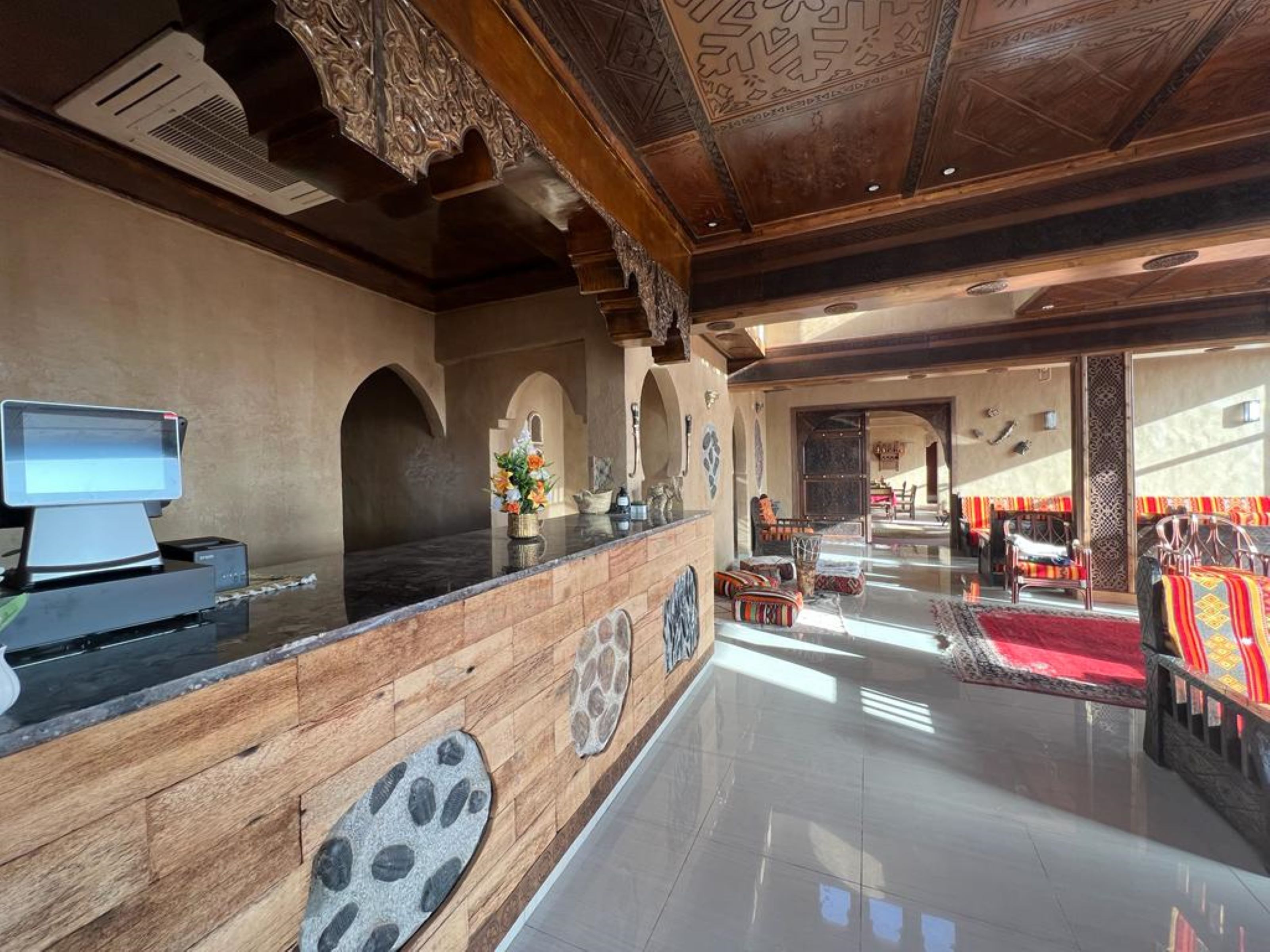 A reception area with a wooden counter, a computer monitor, and a decorative wall with stone patterns.
