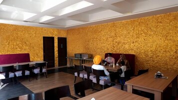 Un restaurante con un diseño rústico en la pared, mesas y sillas de madera.