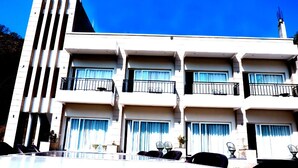 Un hotel de varios pisos con balcones, ventanas grandes y techo plano.