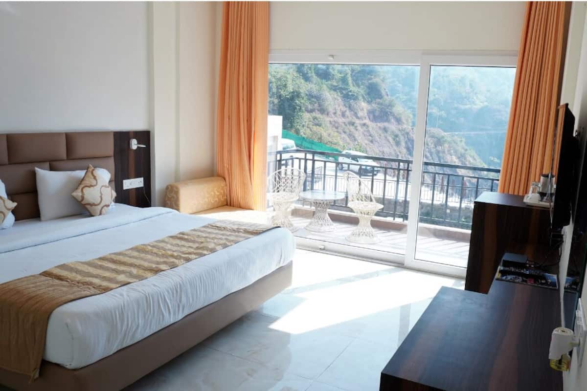 Ein Schlafzimmer mit einem großen Bett, einem Schreibtisch und einem Balkon mit Blick auf eine Berglandschaft.
