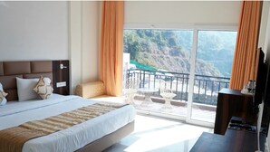 Un dormitorio con una cama grande, un escritorio y un balcón con vistas a un paisaje montañoso.