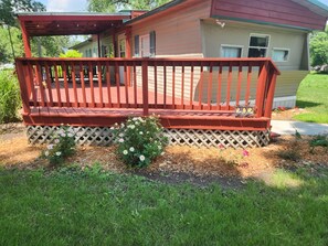 A house with a red porch, a small garden with flowers, and a mailbox.