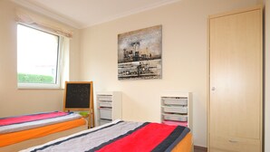 Een slaapkamer met twee bedden, een kledingkast, een schilderij en opbergruimte.