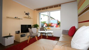 Een woonkamer met een bank, televisie en een bijzettafeltje met een vaas.