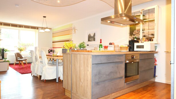 Een moderne keuken met een centraal eiland, een ingebouwde oven en een roestvrijstalen afzuigkap.
