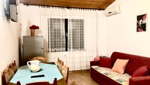 A room with a dining table, chairs, a red sofa, a TV, and an air conditioner. - Nar Apartment A4 1 - With sea View (Pasman)