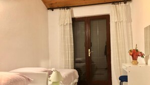 A bedroom with a bed, bedside table, lamp, and a door with curtains. - Nar Apartment A4 1 - With sea View (Pasman)