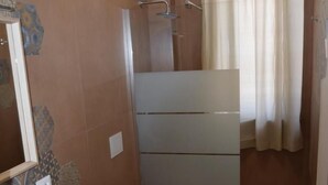 Une petite salle de bain comprenant des toilettes, un lavabo et une douche.