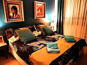 A bedroom with a bed, pillows, a nightstand, a lamp, and a table with folded towels. - La Nogalera 118M2 sea and pool view, central, near beach and transport (Torremolinos)