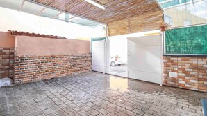 Un espace intérieur avec un mur en briques, un plafond en bois et une porte en verre donnant sur l’extérieur.
