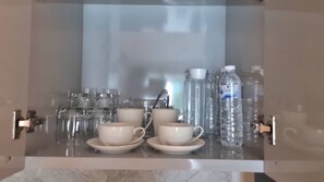 Un mueble con puerta de vidrio que contiene diferentes vasos y botellas de agua.