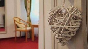 A room with a white door, a wicker heart-shaped decoration, a wooden chair, and a red carpet. - Room in Guest Room - Pension Forelle - Double Room (Forbach)