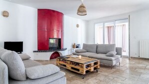 Een moderne woonkamer met een bank, een salontafel, een rode accentmuur en een open haard.