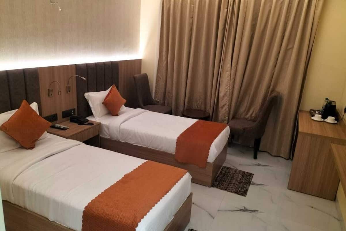 Ein Hotelzimmer mit zwei Betten, einem Schreibtisch, einem Stuhl und einem Vorhang.