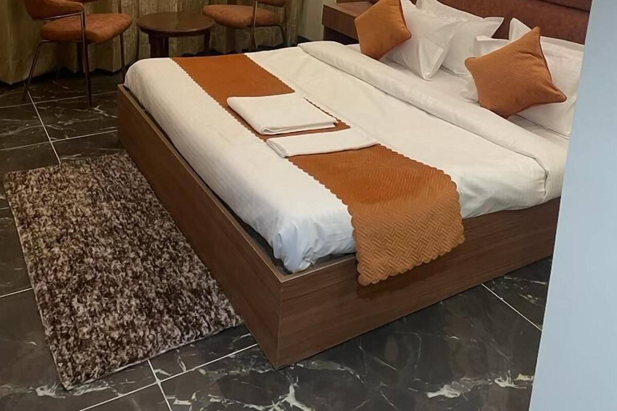 Ein Hotelzimmer mit einem großen Bett, zwei Sesseln, einem kleinen Tisch und einem Vorhang.