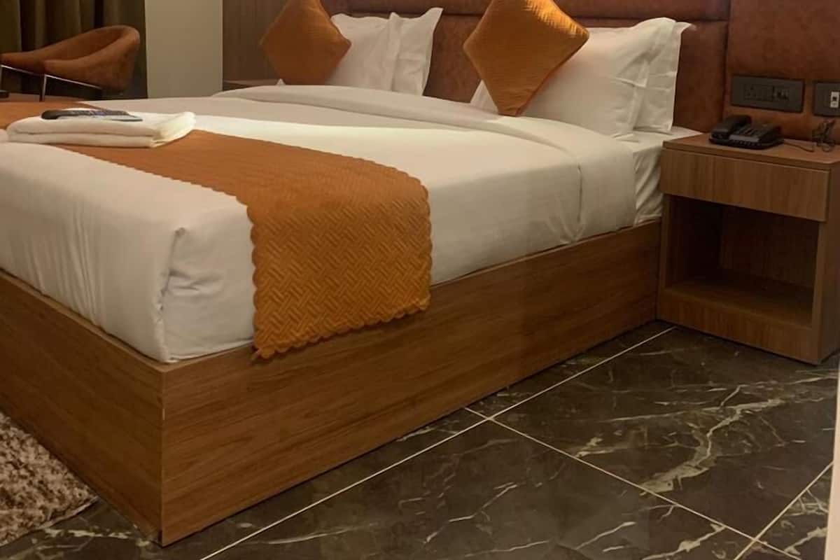 Ein modernes Hotelzimmer mit einem Bettgestell aus Holz, weißen Leinen und einer braunen Tagesdecke.
