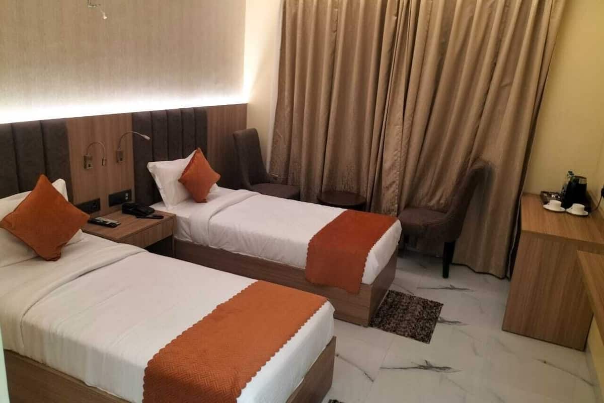 Ein Hotelzimmer mit zwei Betten, einem Schreibtisch, einem Stuhl und einem fenster mit Vorhängen.