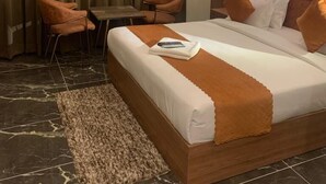 A hotel room with a large bed, a desk, two chairs, a ceiling fan, and a view of the city. - Culture by BVH Hospitality Greater Noida (Greater Noida)