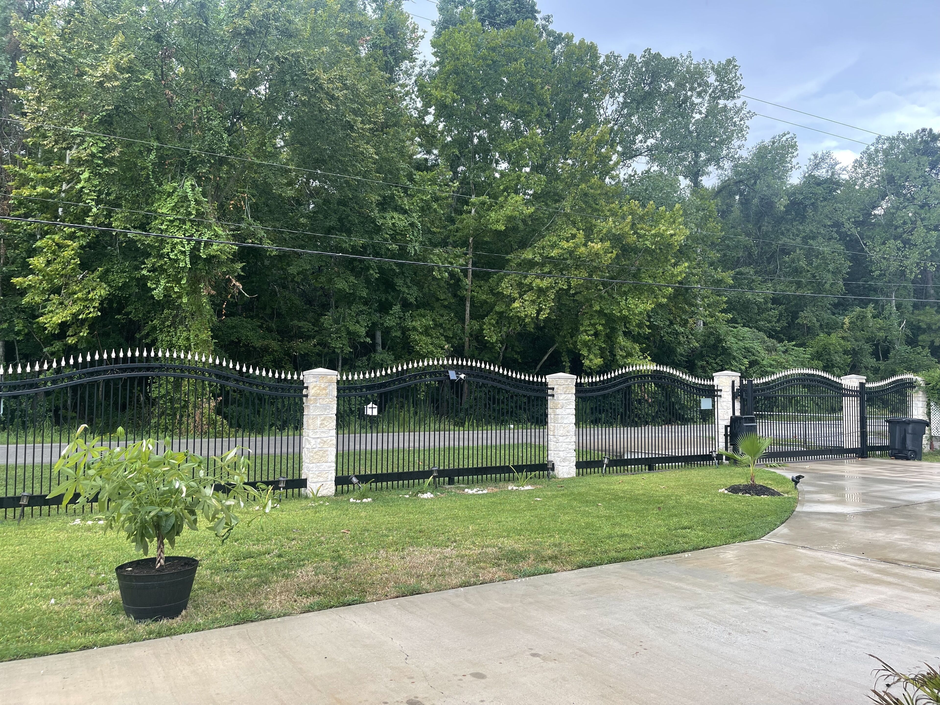 A gated property with a paved driveway and a well-maintained lawn.