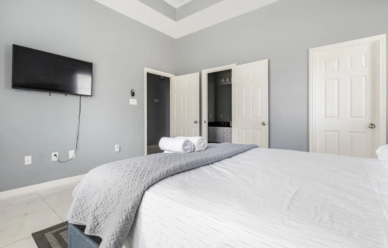A hotel room with a large bed, a flat-screen TV mounted on the wall, and a walk-in closet.