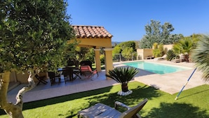 A backyard with a swimming pool, patio furniture, and a pergola.