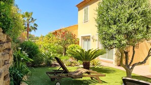 A well-maintained garden with a lawn, a wooden bench, and a wheelbarrow.