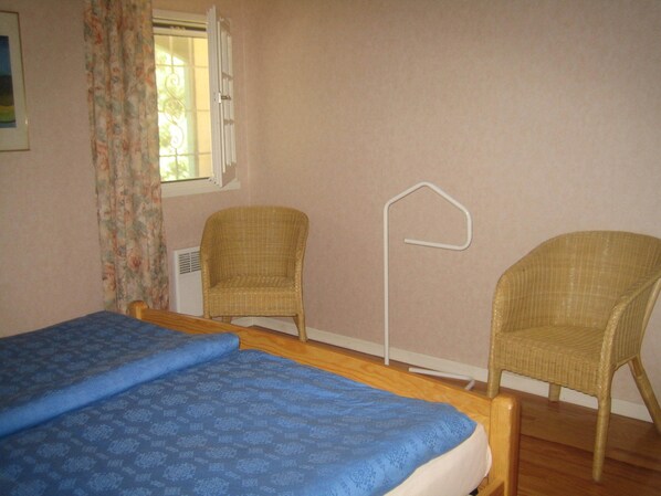 A room with two beds, two wicker chairs, a window with curtains, and a radiator. - Villa La belle Vie (Messanges)
