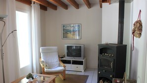 Un soggiorno con televisione, una poltrona, un tavolino in vetro, un camino e un quadro appeso al muro.