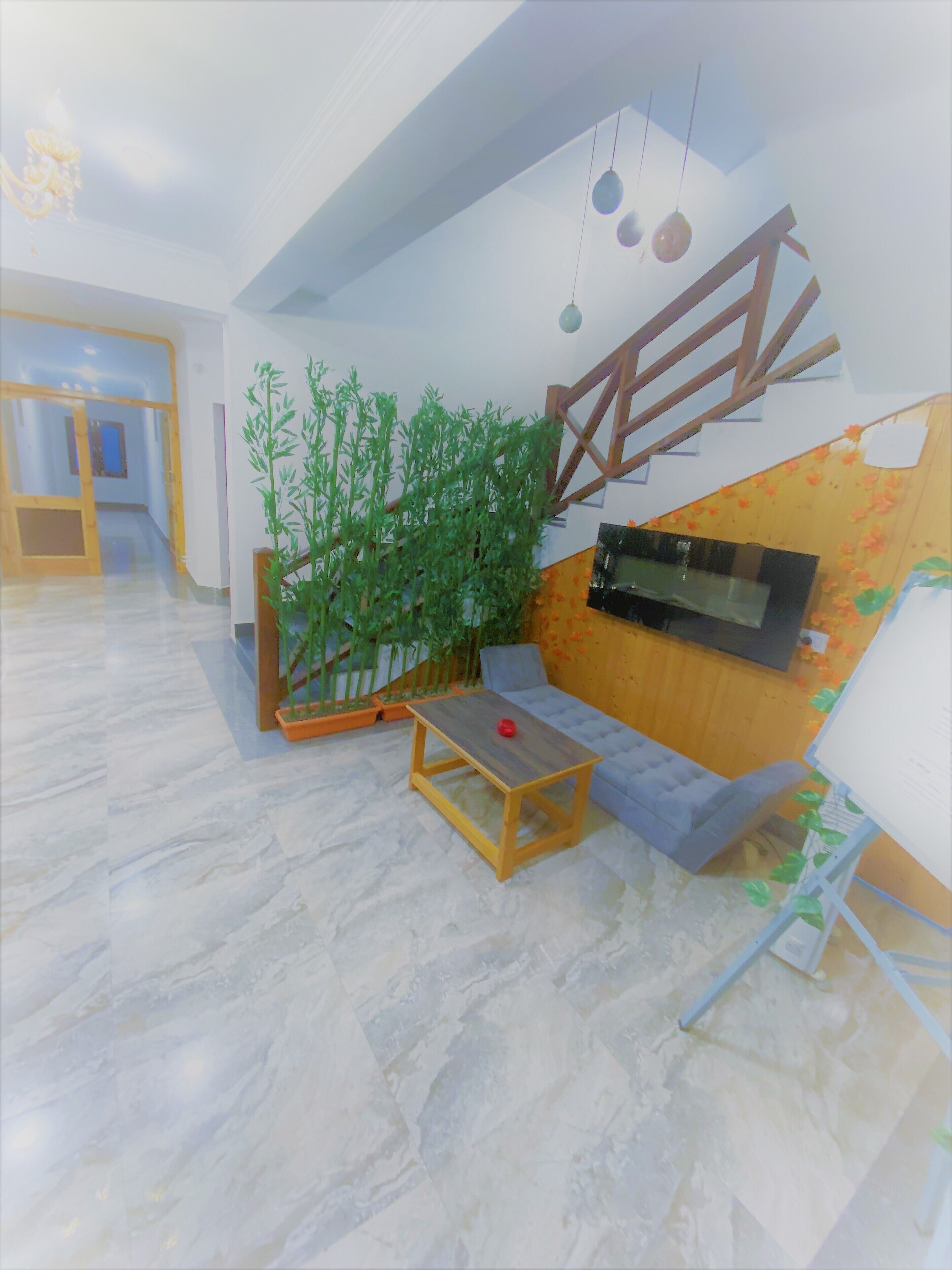 Uma sala de estar moderna com um sofá, uma pequena mesa de madeira, uma TV e uma escada.