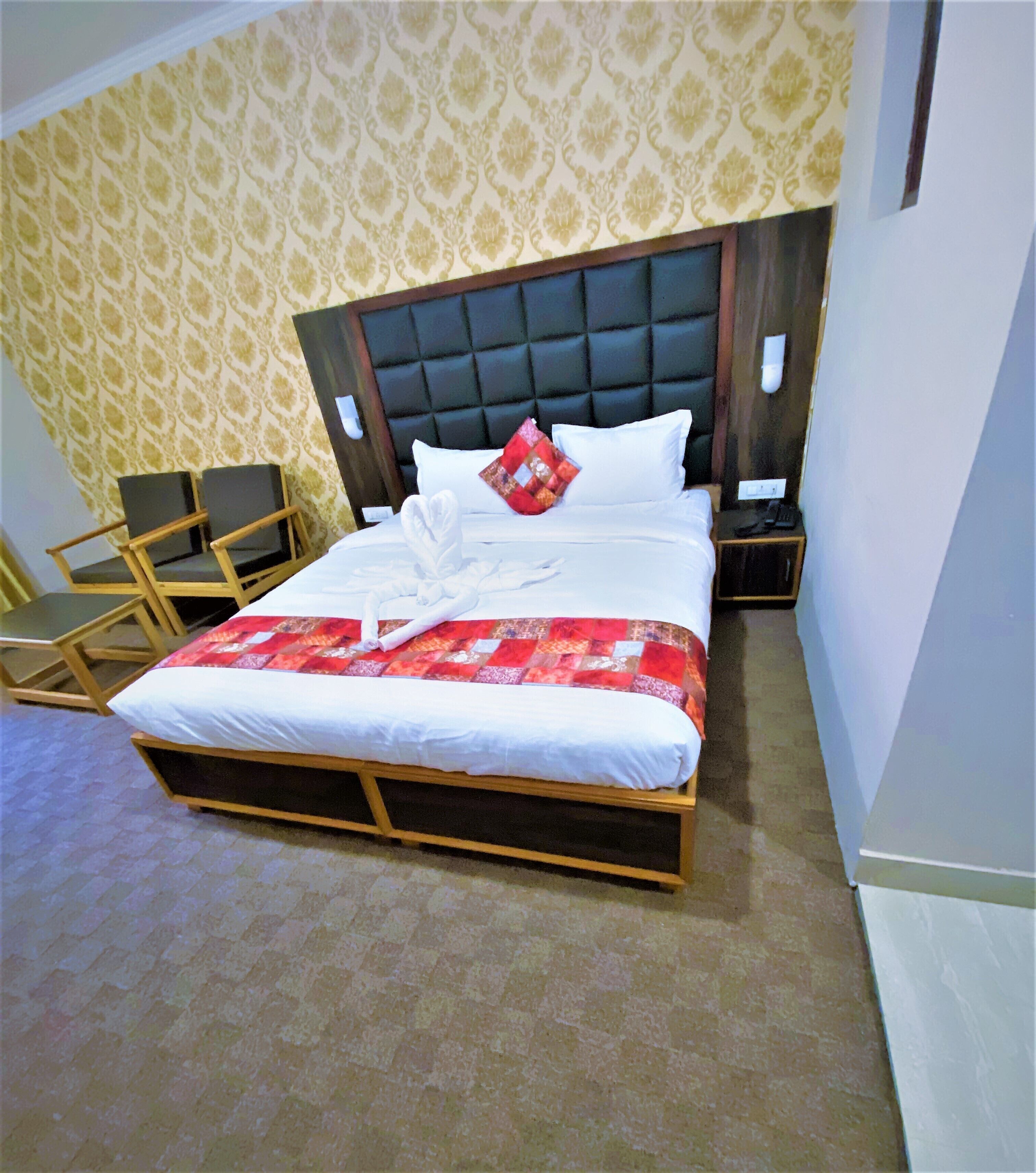 A neatly made bed with a quilt, a wooden headboard, and a bedside table with a phone.