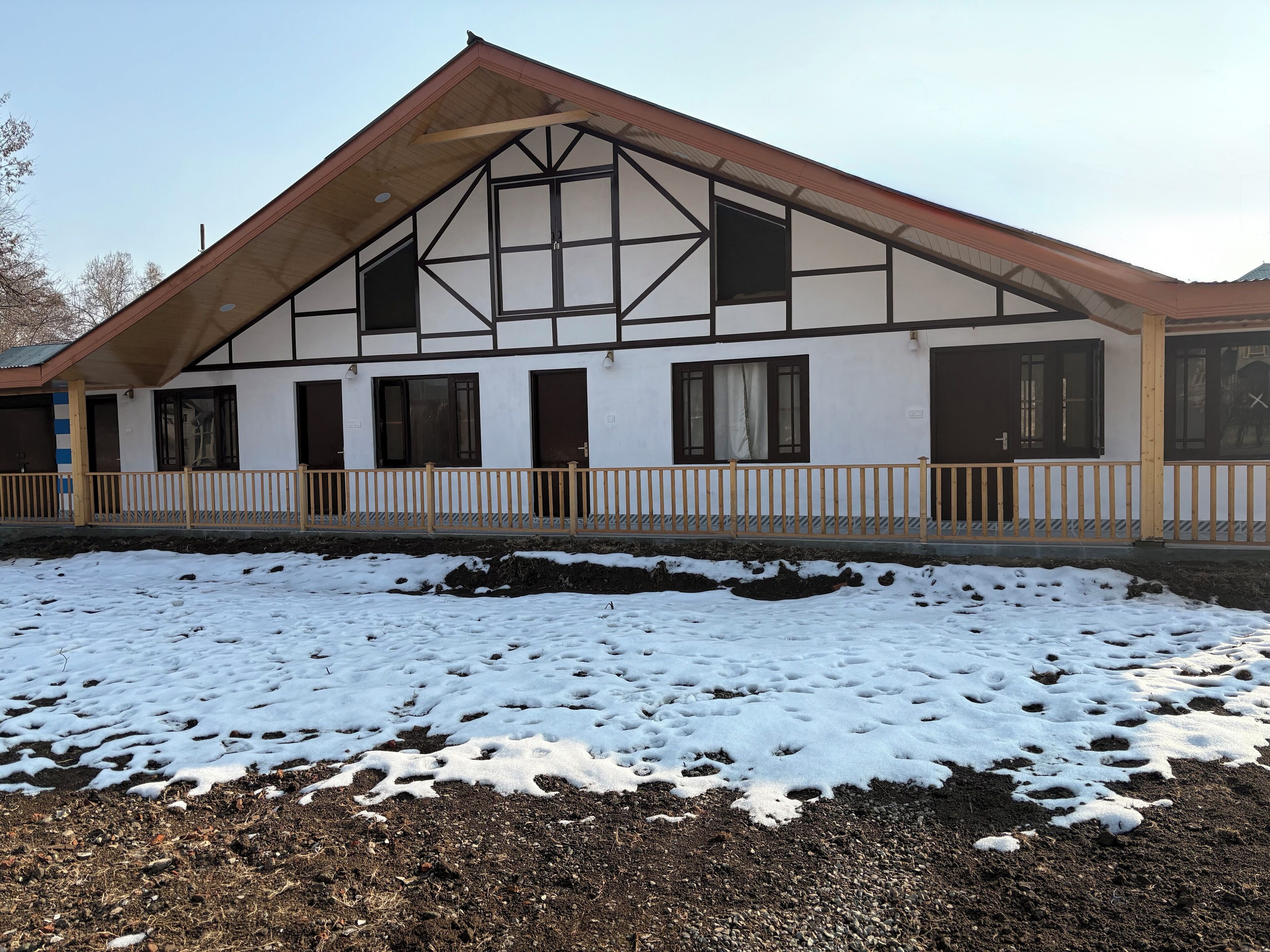 A building with a gabled roof, multiple windows, and a wooden fence.