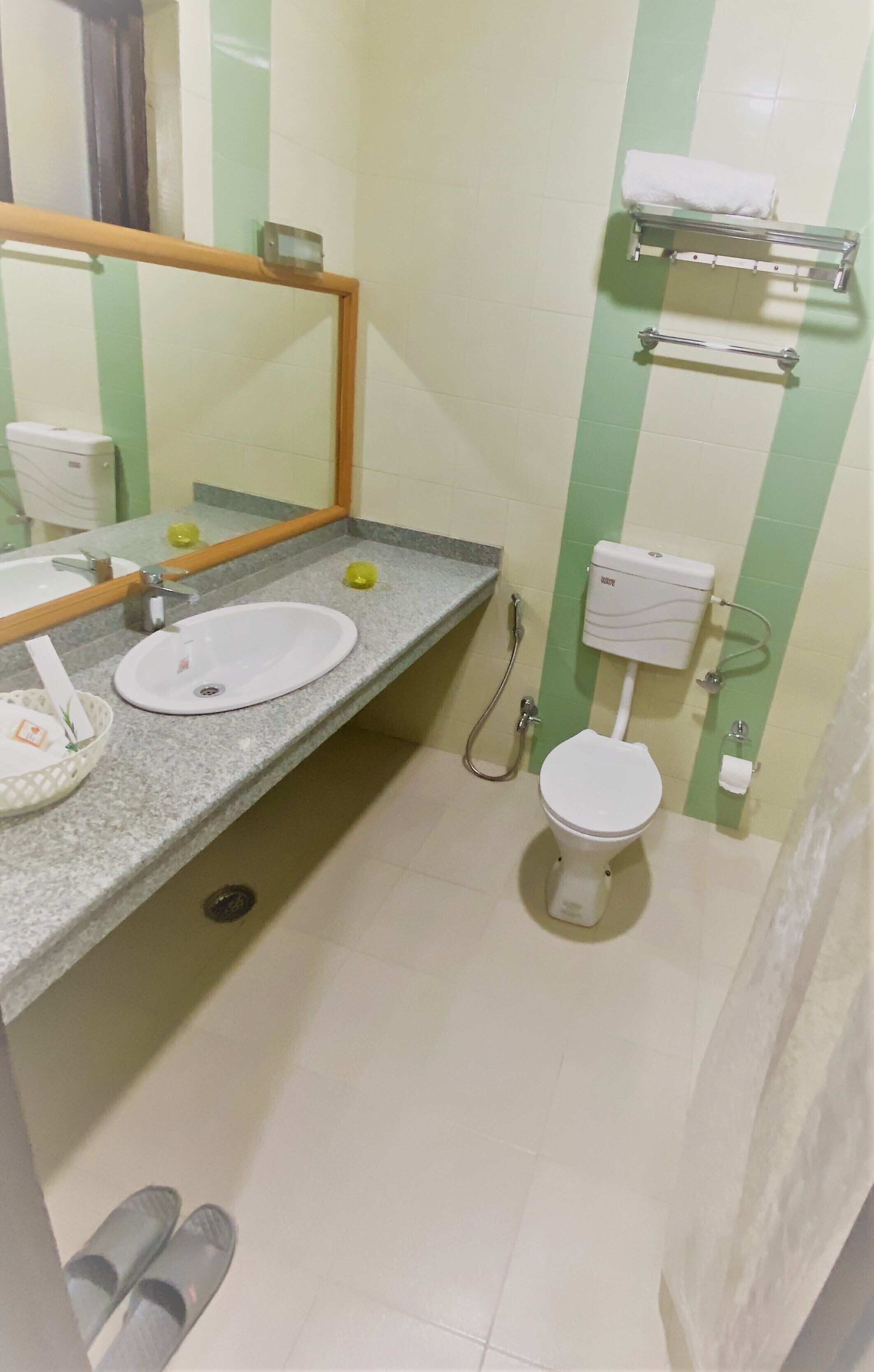 Un baño con lavamanos, espejo, inodoro y toallero.