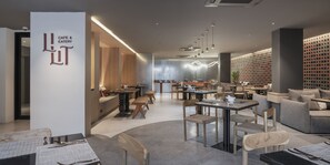 Un café moderne avec des meubles en bois, un coin bar et un espace salon avec des tables et des chaises.
