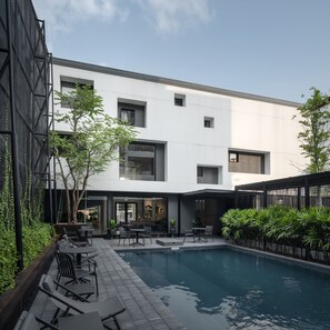 Un bâtiment moderne doté d’une piscine, d’un espace extérieur aménagé et de verdure.