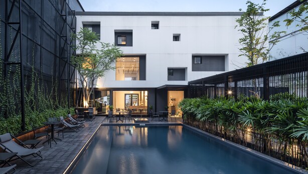 A modern building with a pool, outdoor seating, and greenery. - Lilit Bang Lumphu Hotel (Bangkok)