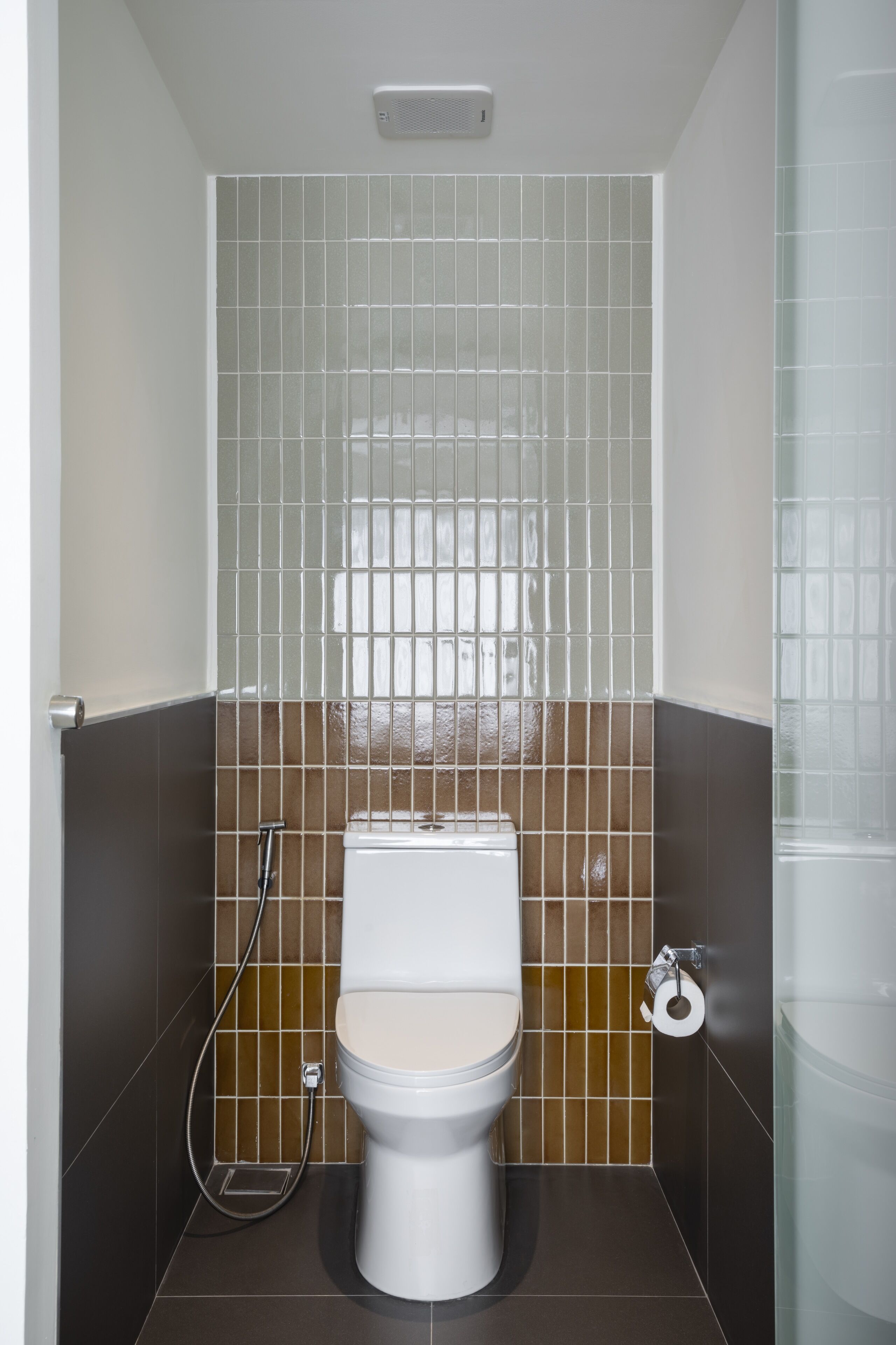 Ein kleines Badezimmer mit Toilette, Dusche und Toilettenpapierhalter.