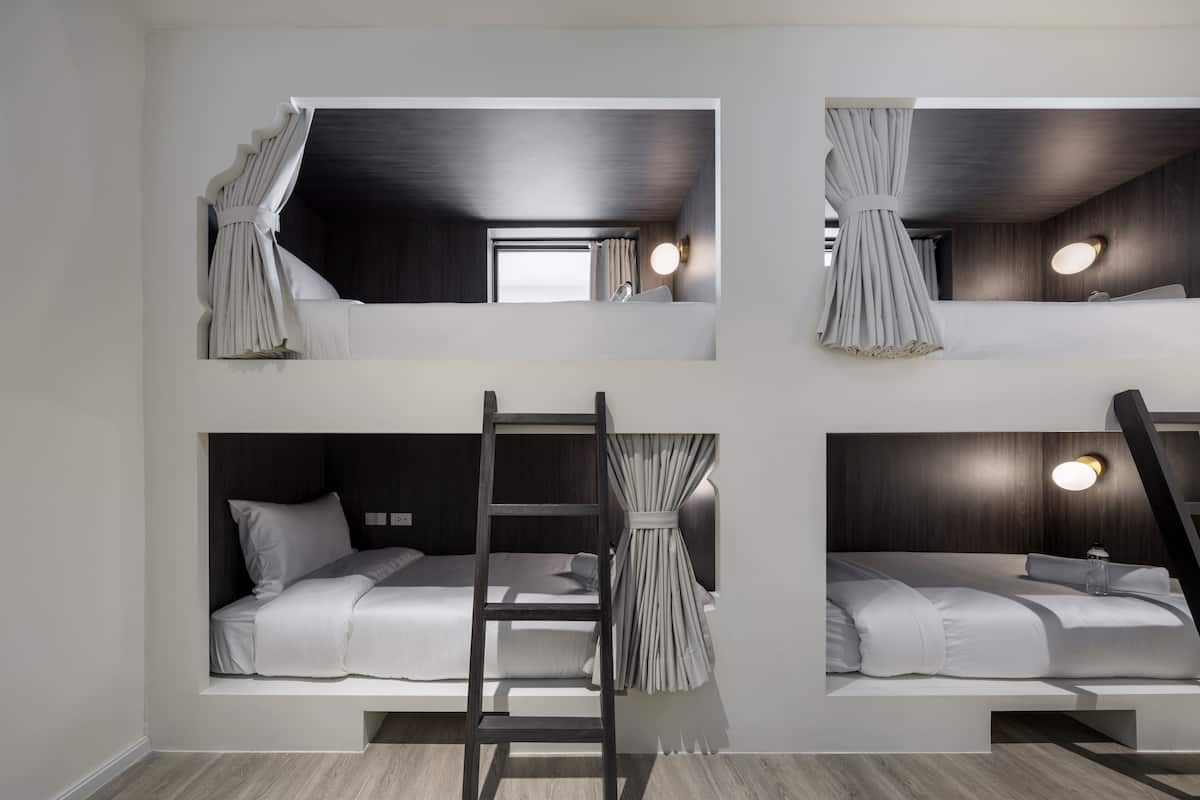 Habitación con literas de varios niveles, una escalera y cortinas.