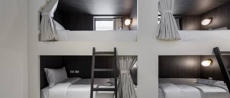 A multi-level bunk bed room with a ladder and curtains.