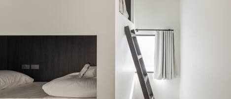 A modern, minimalist bedroom with a bunk bed, a ladder, and a window with curtains.