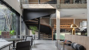 A modern interior with a spacious seating area, a staircase, and a bar area. - Lilit Bang Lumphu Hotel (Bangkok)