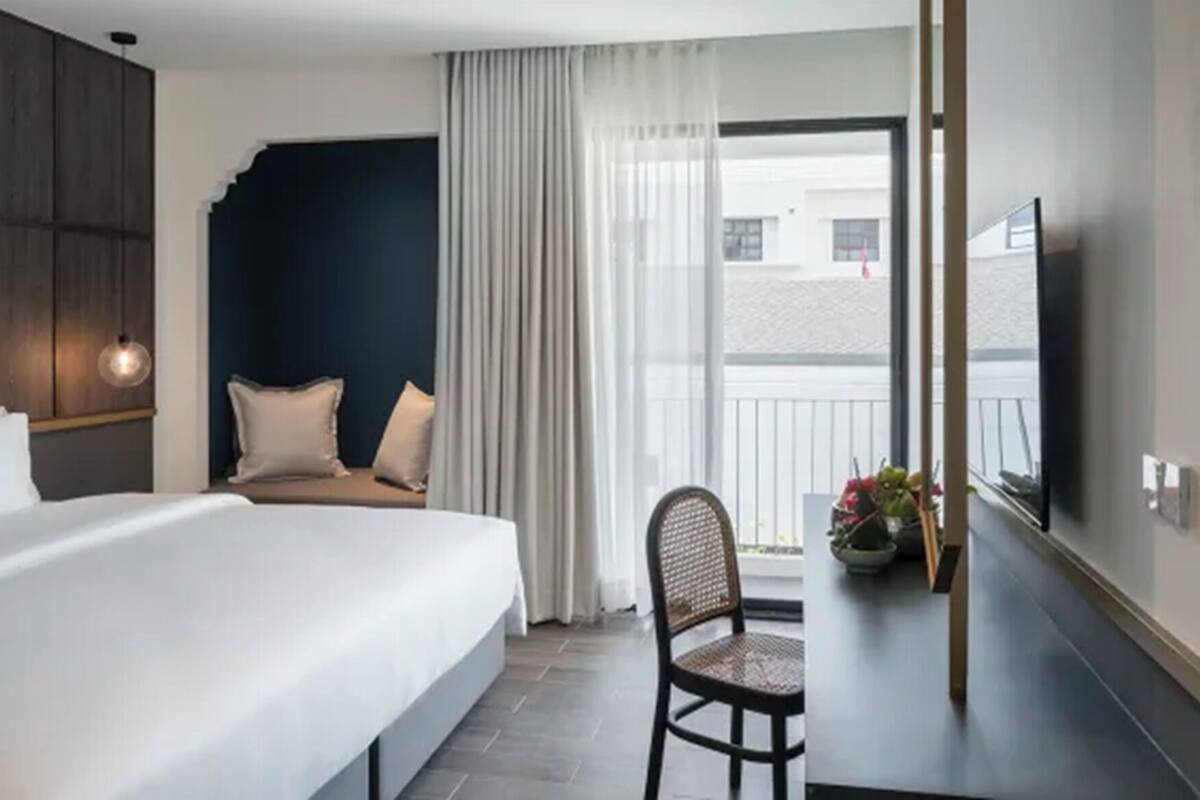Habitación de hotel con cama, una silla, un escritorio, un televisor y vistas al exterior.