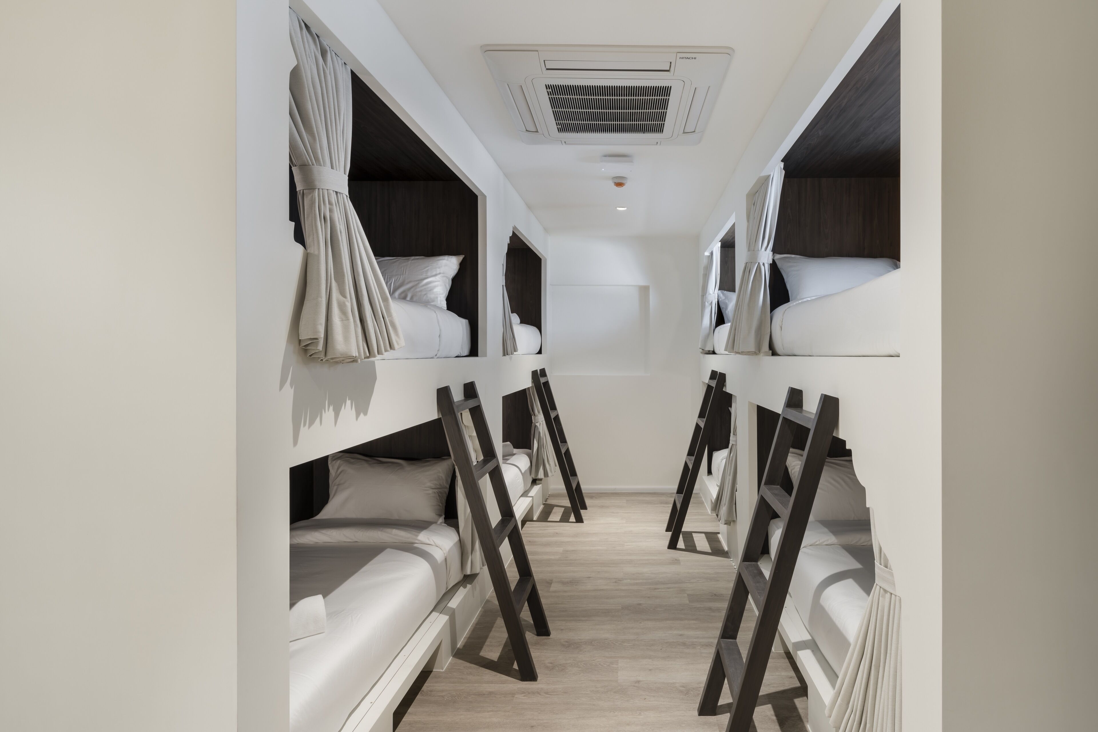 A corridor with bunk beds, a ceiling air conditioner, and a light fixture.